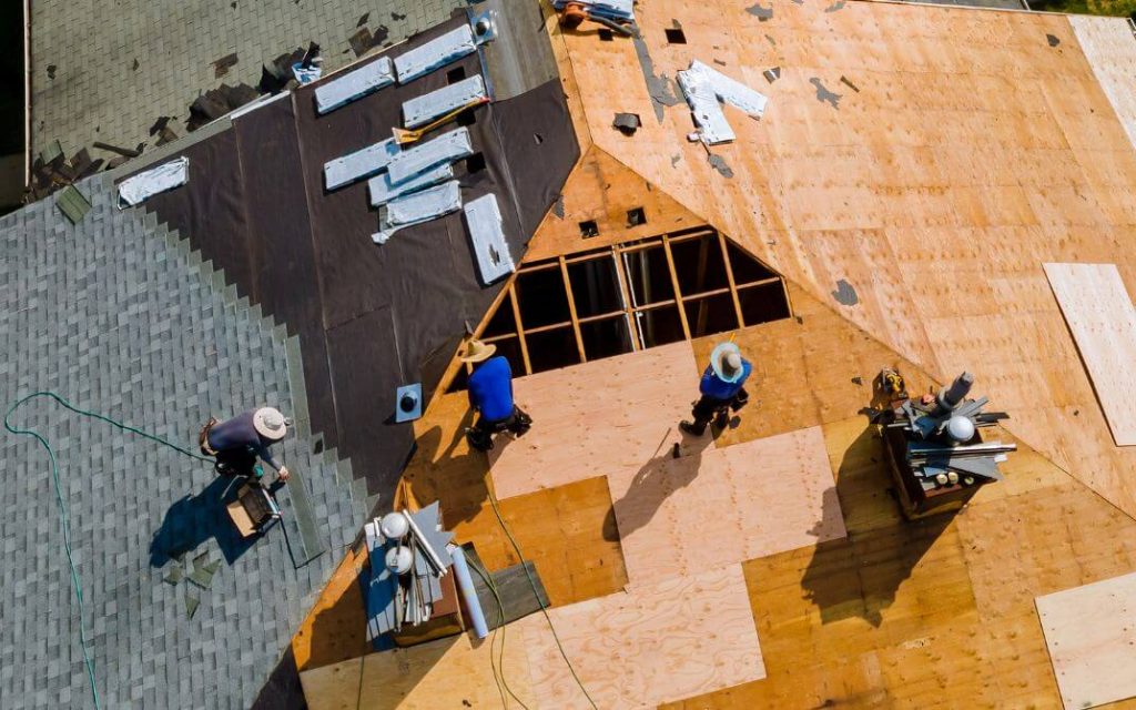 three workers working on a commercial roofing