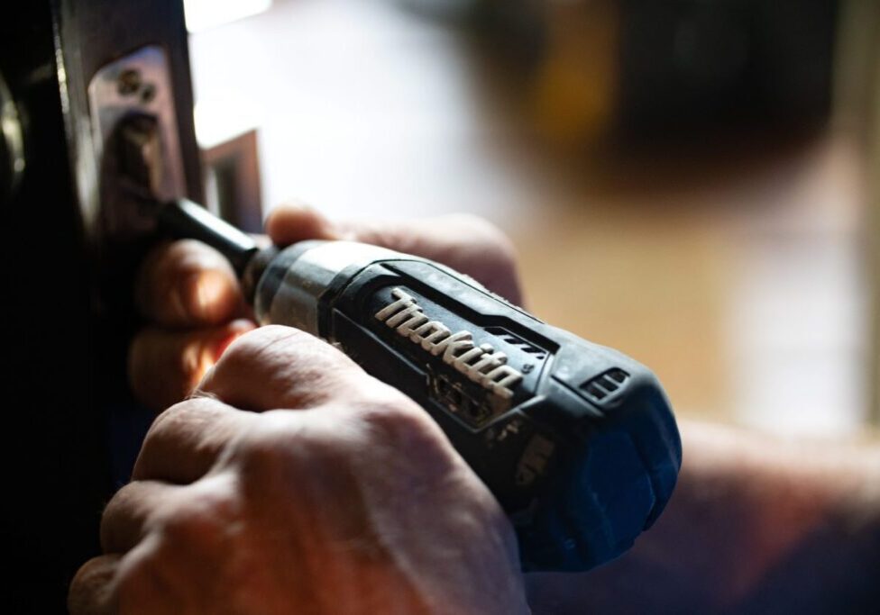 a man is using a cordless drill to open a door